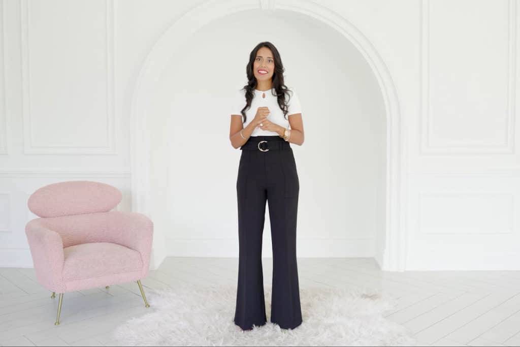 Ritu Bhasin wearing a white top and black pants standing and speaking