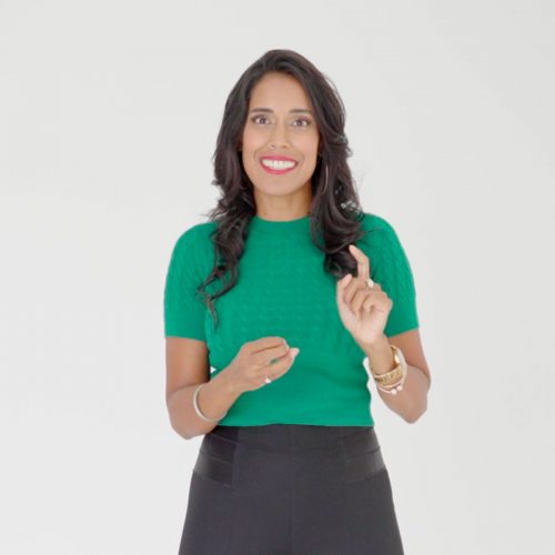 Ritu Bhasin wearing a green top smiling with one hand point up