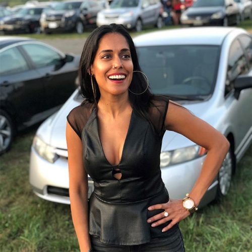 Ritu Bhasin smiling with her hand on her hip, wearing a sleeveless black top.